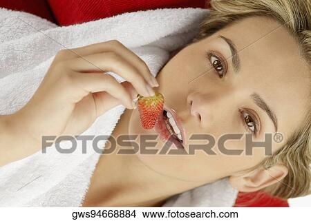 Picture - Portrait of a young woman holding a strawberry. Fotosearch
