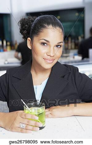 Portrait of a young woman holding a glass of cocktail View Large Photo Image Stock Photography - Portrait of a young woman holding a glass of cocktail. Fotosearch