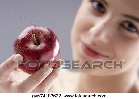 Portrait of a young woman holding an apple View Large Photo Image Stock Image - Portrait of a young woman holding an apple. Fotosearch