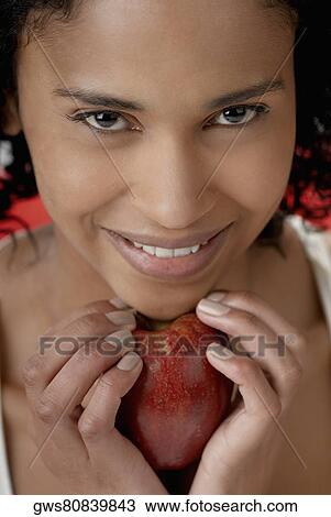 Portrait of a young woman holding an apple under her chin View Large Photo Image Stock Image - Portrait of a young woman holding an apple under her chin. Fotosearch