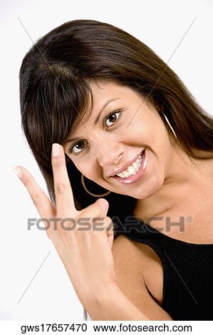 Portrait of a young woman making a peace sign and smiling View Large Photo Image Stock Image - Portrait of a young woman making a peace sign and smiling. Fotosearch