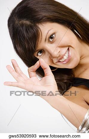 Portrait of a young woman making an OK sign and smiling View Large Photo Image Stock Image - Portrait of a young woman making an OK sign and smiling. Fotosearch