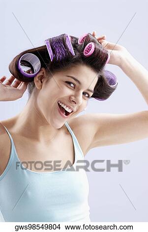 Portrait of a young woman putting curlers in her hair View Large Photo Image Picture - Portrait of a young woman putting curlers in her hair. Fotosearch
