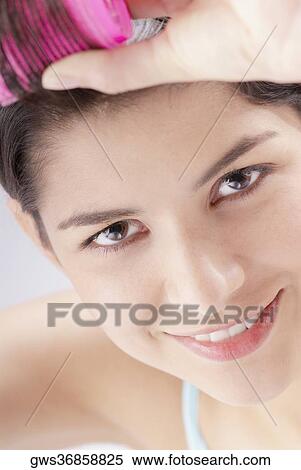 Portrait of a young woman putting curlers in her hair View Large Photo Image Stock Photography - Portrait of a young woman putting curlers in her hair. Fotosearch