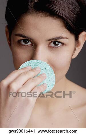 Portrait of a young woman scrubbing her nose with a sponge View Large Photo Image Stock Image - Portrait of a young woman scrubbing her nose with a sponge. Fotosearch