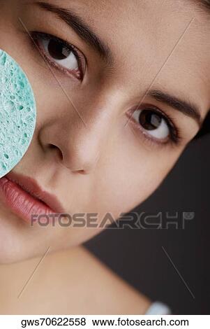 Portrait of a young woman scrubbing her face with a sponge View Large Photo Image Stock Photo - Portrait of a young woman scrubbing her face with a sponge. Fotosearch