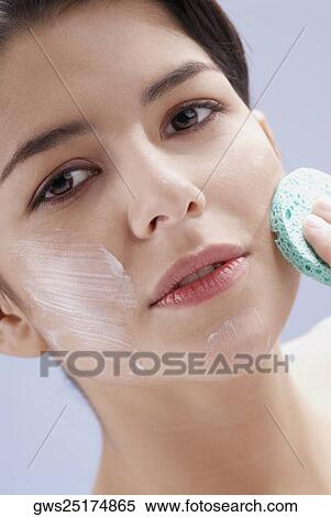 Portrait of a young woman scrubbing her face with a sponge View Large Photo Image Stock Photography - Portrait of a young woman scrubbing her face with a sponge. Fotosearch
