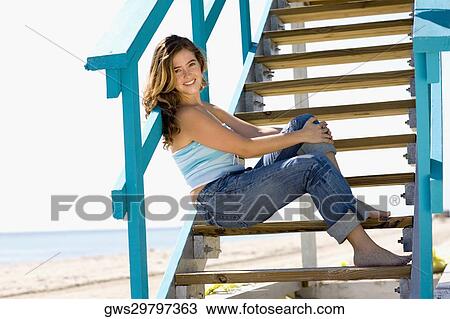 Portrait of a young woman sitting on a staircase of a lifeguard hut and smiling View Large Photo Image Stock Image - Portrait of a young woman sitting on a staircase of a lifeguard hut and smiling. Fotosearch