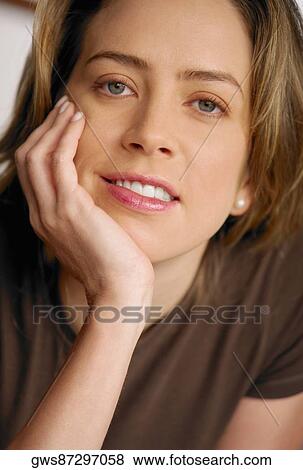 Portrait of a young woman smiling with her hand on her chin View Large Photo Image Stock Photo - Portrait of a young woman smiling with her hand on her chin. Fotosearch