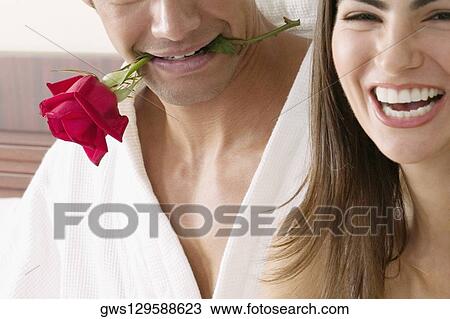 Portrait of a young woman with a young man holding a rose in his mouth View Large Photo Image Stock Image - Portrait of a young woman with a young man holding a rose in his mouth. Fotosearch