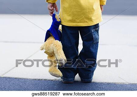 Rear view of a boy holding a teddy bear View Large Photo Image Stock Photo - Rear view of a boy holding a teddy bear. Fotosearch