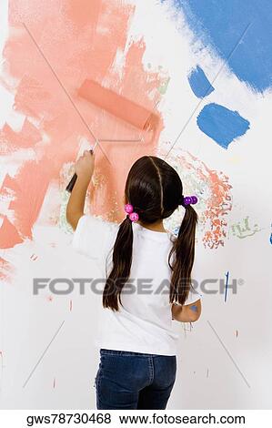 Rear view of a girl painting a wall with a paint roller View Large Photo Image Stock Photo - Rear view of a girl painting a wall with a paint roller. Fotosearch