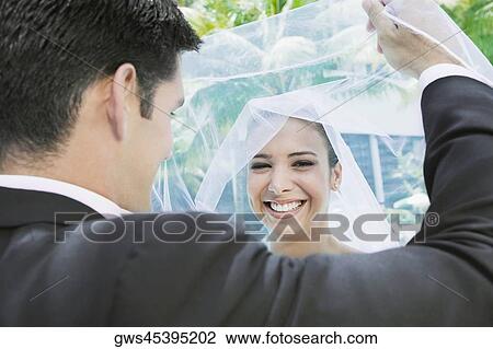 Rear view of a groom lifting his bride's veil View Large Photo Image Stock Image - Rear view of a groom lifting his bride's veil. Fotosearch
