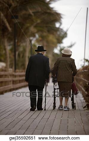 Rear view of a man and a woman walking on a boardwalk with a baby stroller View Large Photo Image Stock Image - Rear view of a man and a woman walking on a boardwalk with a baby stroller. Fotosearch