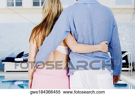 Rear view of a man and woman standing with their arms around each other View Large Photo Image Stock Photography - Rear view of a man and woman standing with their arms around each other. Fotosearch