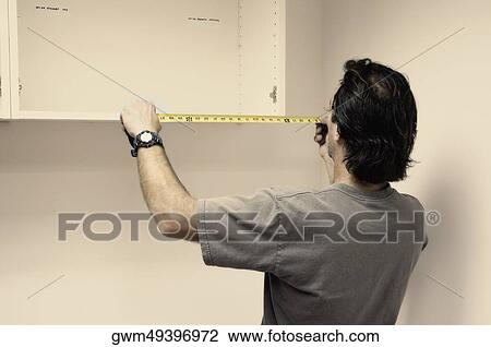 Rear view of a man measuring a wooden board with a tape measure View Large Photo Image Stock Image - Rear view of a man measuring a wooden board with a tape measure. Fotosearch