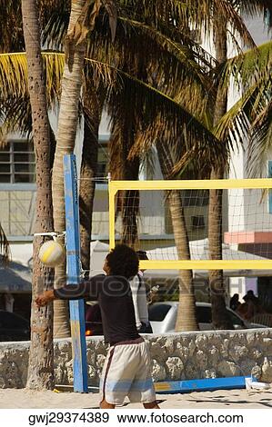 Stock Photo - Rear view of a man playing volleyball on the beach, Miami Beach, Florida, USA. Fotosearch