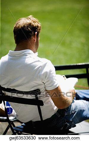 Rear view of a man reading a book View Large Photo Image Stock Image - Rear view of a man reading a book. Fotosearch