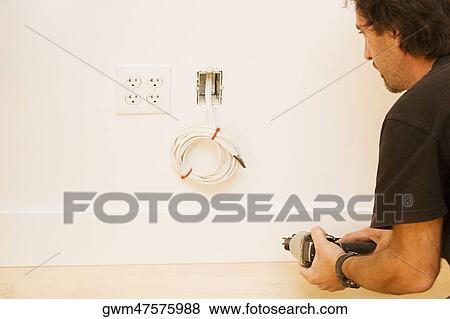 Stock Photo - Rear view of a mid adult man holding a hand drill. Fotosearch