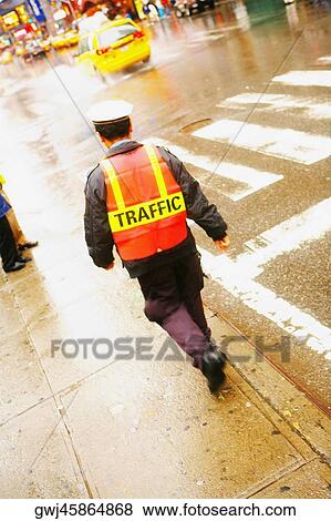 Stock Photo - Rear view of a traffic cop walking on the road. Fotosearch