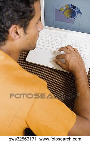 Rear view of a young man using a laptop View Large Photo Image Stock Image - Rear view of a young man using a laptop. Fotosearch