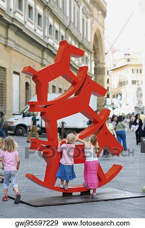 Rear view of two girls climbing a rocking horse sculpture, Venice, Veneto, Italy View Large Photo Image Stock Photo - Rear view of two girls climbing a rocking horse sculpture, Venice, Veneto, Italy. Fotosearch