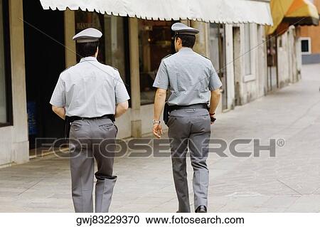 Rear view of two policemen walking towards a building, Venice, Veneto, Italy View Large Photo Image Stock Image - Rear view of two policemen walking towards a building, Venice, Veneto, Italy. Fotosearch