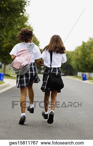Rear view of two schoolgirls walking with holding hands View Large Photo Image Stock Photo - Rear view of two schoolgirls walking with holding hands. Fotosearch