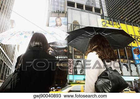 Rear view of two women standing at the roadside View Large Photo Image Stock Image - Rear view of two women standing at the roadside. Fotosearch