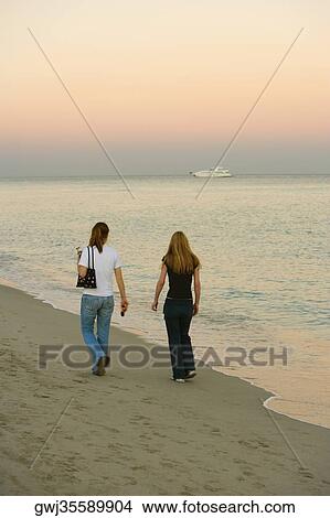 Picture - Rear view of two women walking on the beach. Fotosearch