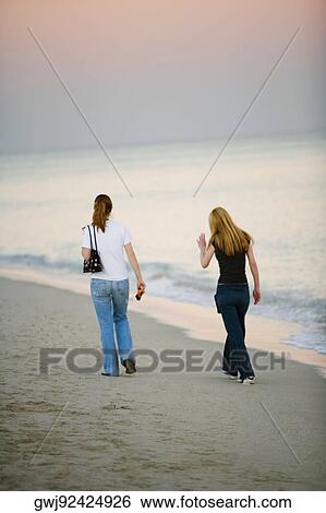 Rear view of two women walking on the beach View Large Photo Image Stock Photograph - Rear view of two women walking on the beach. Fotosearch