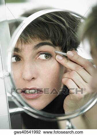 Reflection of a mature woman tweezing her eyebrows in a mirror View Large Photo Image Stock Image - Reflection of a mature woman tweezing her eyebrows in a mirror. Fotosearch
