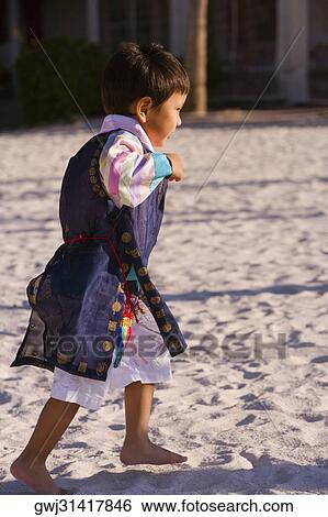 Side profile of a boy in traditional clothing walking on sand View Large Photo Image Stock Photograph - Side profile of a boy in traditional clothing walking on sand. Fotosearch