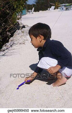 Side profile of a boy playing in sand View Large Photo Image Stock Image - Side profile of a boy playing in sand. Fotosearch