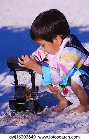 Stock Photo - Side profile of a boy playing with a toy on the beach. Fotosearch
