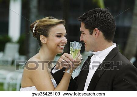Side profile of a bride and her groom toasting with champagne flutes View Large Photo Image Stock Photo - Side profile of a bride and her groom toasting with champagne flutes. Fotosearch