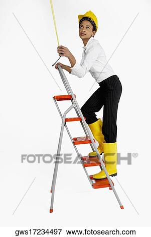 Side profile of a female architect climbing a ladder and holding a tape measure View Large Photo Image Stock Photo - Side profile of a female architect climbing a ladder and holding a tape measure. Fotosearch