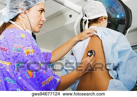 Side profile of a female doctor examining a female patient with a stethoscope View Large Photo Image Picture - Side profile of a female doctor examining a female patient with a stethoscope. Fotosearch