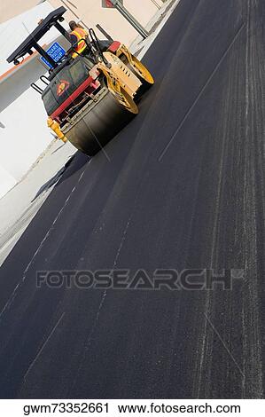 Stock Image - Side profile of a man sitting on a steamroller. Fotosearch