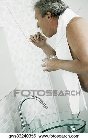 Side profile of a mature man brushing his teeth in a mirror View Large Photo Image Stock Photograph - Side profile of a mature man brushing his teeth in a mirror. Fotosearch