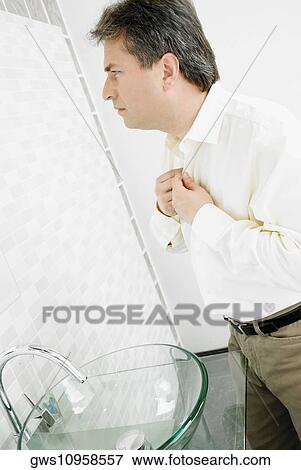 Side profile of a mature man buttoning his shirt in the bathroom View Large Photo Image Stock Photo - Side profile of a mature man buttoning his shirt in the bathroom. Fotosearch