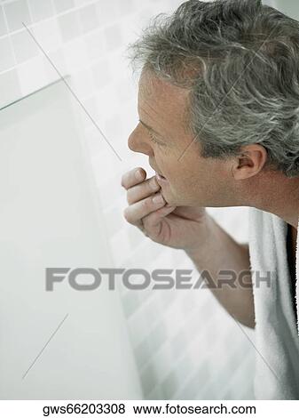 Side profile of a mature man touching his face in a mirror View Large Photo Image Stock Photo - Side profile of a mature man touching his face in a mirror. Fotosearch