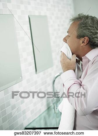 Side profile of a mature man wiping his face with a towel in front of a mirror View Large Photo Image Stock Photo - Side profile of a mature man wiping his face with a towel in front of a mirror. Fotosearch