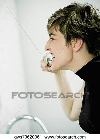 Side profile of a mature woman brushing her teeth View Large Photo Image Stock Image - Side profile of a mature woman brushing her teeth. Fotosearch