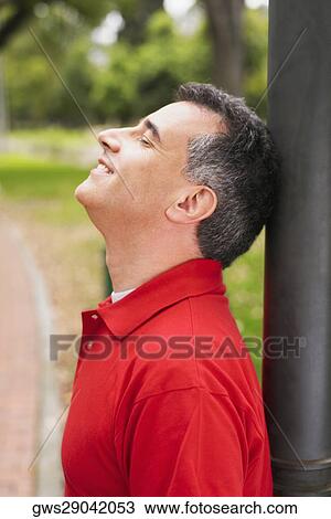 Side profile of a mid adult man leaning against a pole View Large Photo Image Stock Image - Side profile of a mid adult man leaning against a pole. Fotosearch