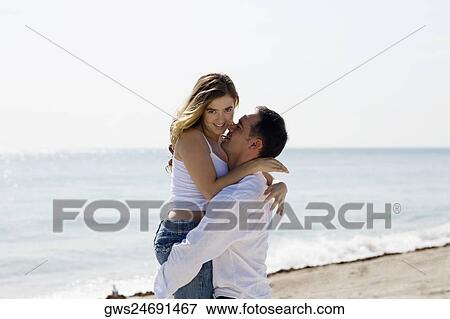 Side profile of a mid adult man lifting a young woman on the beach View Large Photo Image Stock Photo - Side profile of a mid adult man lifting a young woman on the beach. Fotosearch