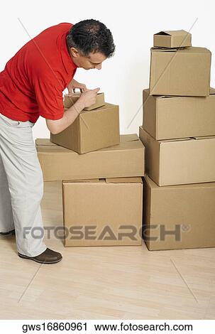 Side profile of a mid adult man packing cardboard boxes View Large Photo Image Stock Image - Side profile of a mid adult man packing cardboard boxes. Fotosearch