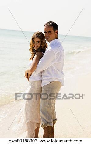 Side profile of a mid adult man embracing a young woman from behind on the beach View Large Photo Image Stock Image - Side profile of a mid adult man embracing a young woman from behind on the beach. Fotosearch