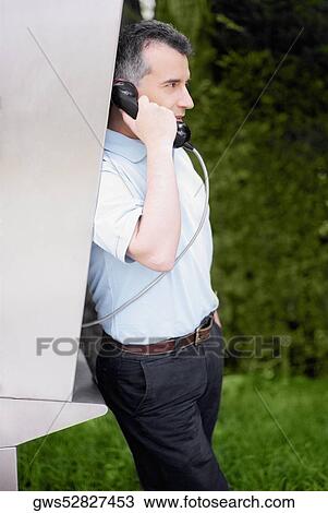 Side profile of a mid adult man talking on a pay phone View Large Photo Image Stock Image - Side profile of a mid adult man talking on a pay phone. Fotosearch