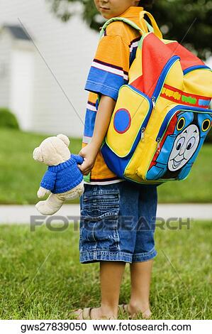 Side profile of a schoolboy carrying a schoolbag and a teddy bear View Large Photo Image Stock Image - Side profile of a schoolboy carrying a schoolbag and a teddy bear. Fotosearch